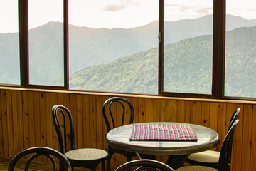 Table, chairs and window with view of Himalayan mountains outside. Sikkim, West Bengal, India.
