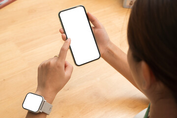 Woman touching smartphone with blank screen while wearing smartwatch, top view modern tech concept