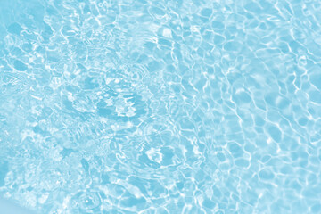Blue water with ripples on the surface. Defocus blurred transparent blue colored clear calm water surface texture with splashes and bubbles. Water waves with shining pattern texture background.