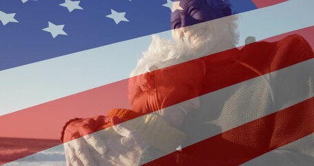 Elderly man carrying partner at water's edge, American flag overlay initiating patriotic tribute - Powered by Adobe