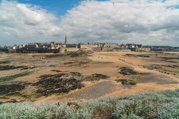 View of the fortress city of Saint-Malo on the English Channel and the ocean floor exposed at low tide on a sunny summer day, Brittany, France