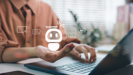 A user is using a laptop with hologram AI assistant icon above hand. Concept of artificial intelligence technology, smart virtual assistant, and generative AI for productivity.