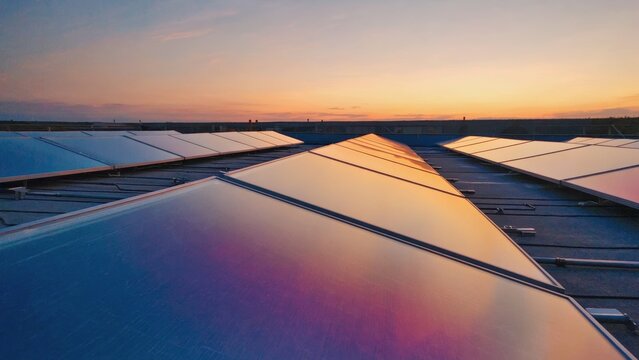 Reflective surface of solar panels capturing colorful twilight sky, representing green energy technology and futuristic solutions for environmental conservation and renewable electricity sources