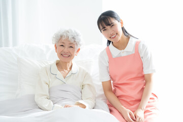 Obraz premium ベッドに寝るシニア女性を介護する介護福祉士