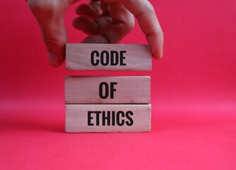 hand holding wooden block representing Code of Ethics writing on red background for Professional Concept
