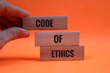 hand holding wooden block representing Code of Ethics writing on Orange background for Professional...