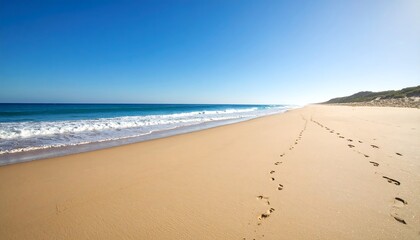 Empty beach, footprints in the sand, bright blue sky