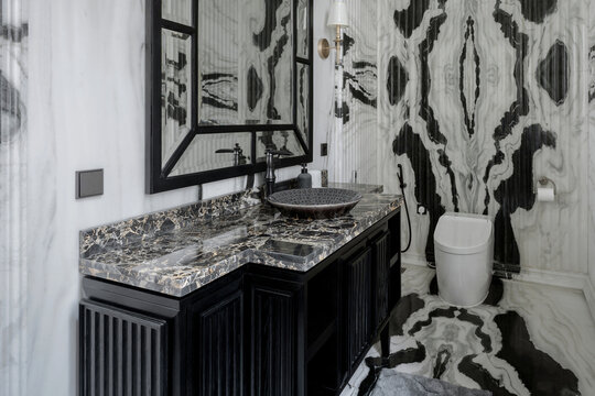 Opulent bathroom featuring bookmatched Panda marble walls, a black vanity, and a modern toilet. A fusion of classic and modern luxury design.