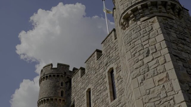 Stone castle tower against a bright, cloudy sky. Architectural detail and a sense of history