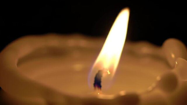 Macro slow motion of melted wax rolling down a lit candle.