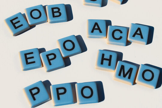 An arrangement of several health insurance term acronyms design element with letter tiles isolated on a white background