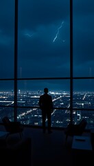 Man silhouette looking at city skyline lightning storm from high rise apartment