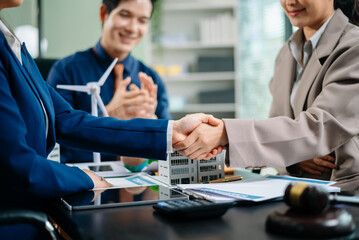 Two businesswomen shake hands after successful eco-friendly deal as colleague applauds. Great for business partnership, sustainability, and teamwork