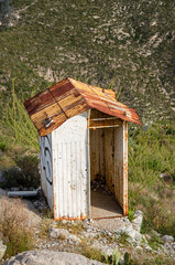 Explore a rustic weathered building with a rusted roof and graffiti in a natural outdoor mountain...