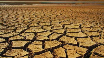 Lifeless desert land with a dry cracked lake bed. Parched soil showing mud cracks due to drought and water scarcity. Harsh environment symbolizing global warming and crisis - Powered by Adobe