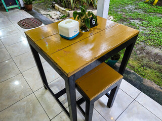 The cafe tables and chairs are made of wood and arranged outdoors.