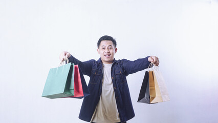 Portrait of excited Asian man with many shopping bags isolated on white background