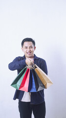 Portrait of smiling Asian man holding shopping bags isolated on white background