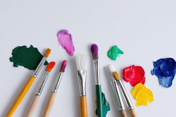 Fototapeta premium Paintbrushes with Colorful Acrylic Paints Surround Blank Canvas Representing Creative Social Activism