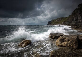 Obraz premium Waves Crashing Against Coastal Rocks Under Stormy Skies with Rugged Cliffs in the Background