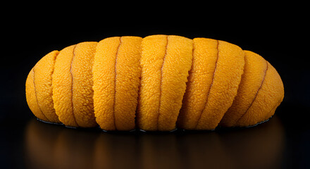 Fresh sea urchin meat (uni), set against a deep black background.