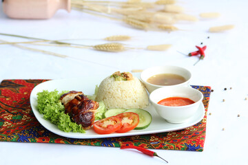 Roasted chicken rice, Southeast Asian dish featuring roasted served with fragrant rice cooked in chicken broth and flavored with aromatics like ginger and garlic accompanied by chili sauce and soup.