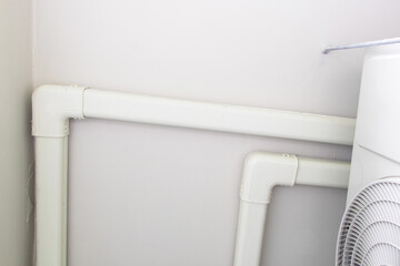 Structure air conditioner pipe, wiring and plumbing system attached to concrete ceiling of building. Plastic wiring, plumbing in mall. Air ducts and water pipes are installed on wall at outdoor.