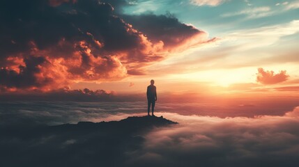 Obraz premium Silhouette of a man standing on a mountain top looking at sunset