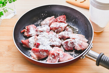 下味をつけた豚肉に粉をふるう