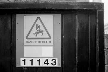 Danger of death sign on wooden door, grainy black and white analog photo