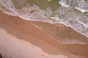Aerial views of waves breaking against the beach over Dreamtime beach in Fingal Head New South Wales, Australia