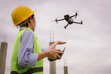 A female construction worker in a safety vest and hard hat operates a drone on-site, using smart technology for surveying, inspection, and monitoring in modern engineering projects.