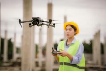 A female construction worker in a safety vest and hard hat operates a drone on-site, using smart technology for surveying, inspection, and monitoring in modern engineering projects.