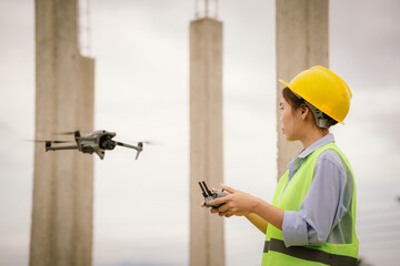 A female construction worker in a safety vest and hard hat operates a drone on-site, using smart technology for surveying, inspection, and monitoring in modern engineering projects.