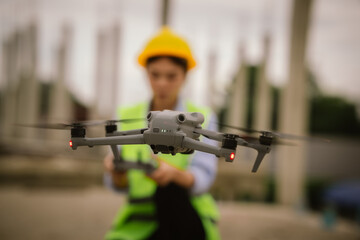 A female engineer in a hard hat and safety vest operates a drone at a construction site, using smart technology for inspection, surveying, and modern infrastructure planning.
