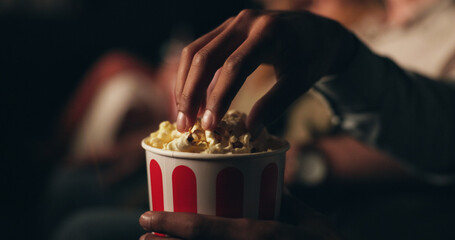 Hands, popcorn and snack at cinema in crowd for film screening, fast food and event for entertainment. Person, eating and relax for show, movies or container with audience at night in theater