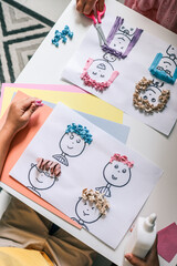 Children making creative paper art with cartoon faces and textured hair from crumpled colored...