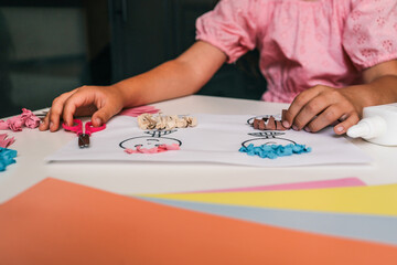 Child creating a paper art project using drawings, colored paper, glue, and scissors. Hands-on...