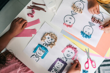 Children making creative paper art with cartoon faces and textured hair from crumpled colored...