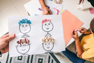 Children making creative paper art with cartoon faces and textured hair from crumpled colored...