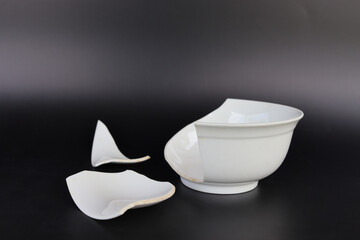 Broken white cup on black background. Concept of breakage, unstable.