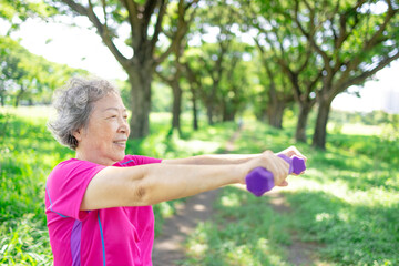 Happy Asian senior woman lifting dumbbell