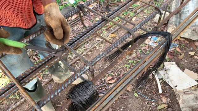 Hands of construction worker that holding a plier to cutting a wire. Making series of iron for foundation and column building. Connect irons for frame pillar. Civil work. Building structure work