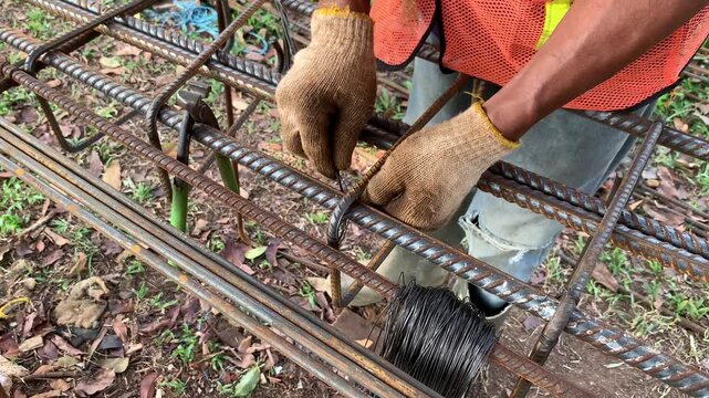 Hands of construction worker that holding a plier to cutting a wire. Making series of iron for foundation and column building. Connect irons for frame pillar. Civil work. Building structure work