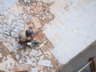 Professional tradesman skillfully removing old tile flooring with power drill during home...