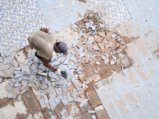 Diligent worker expertly removes old tiles for stunning renovation project in bright sunlight...