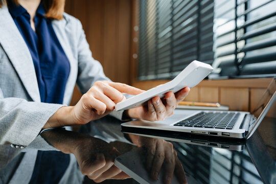 Businesswoman hand working with finances about cost and calculator and laptop with tablet on withe desk