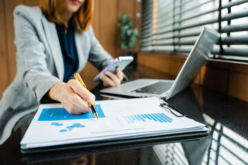 Hands of woman using mobile phone in modern office with laptop and digital tablet at office