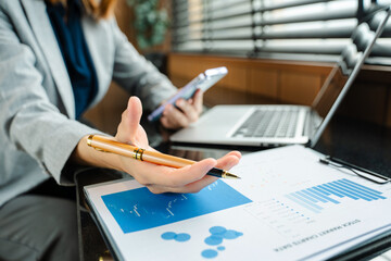 Hands of woman using mobile phone in modern office with laptop and digital tablet at office
