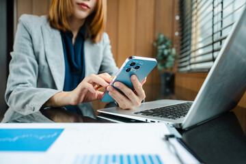 Hands of woman using mobile phone in modern office with laptop and digital tablet at office